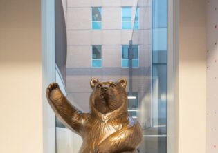 Bear throwing paper airplanes down a hallway. Bronze sculpture in Children's Hospital and Medical Center in Omaha, Nebraska.